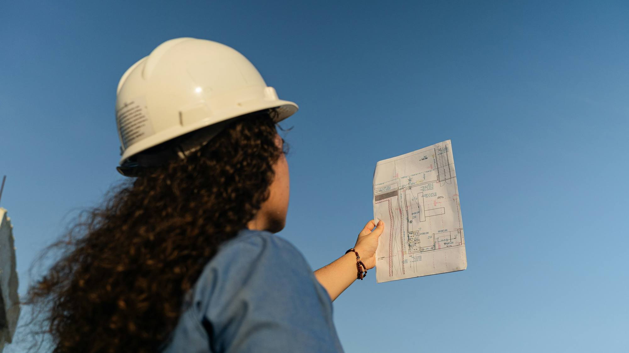 Person in a hard hat reviewing construction drawings